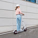 Person riding a scooter with a helmet on a city street.