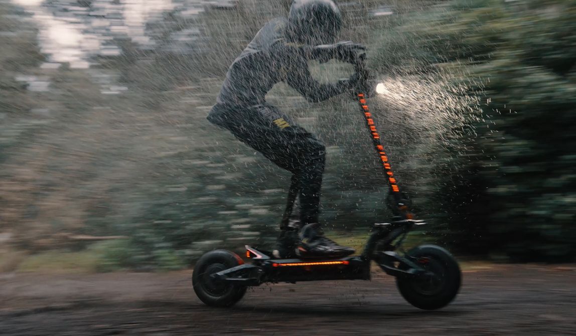 Person riding aTeverun Fughter Supreme Ultra electric scooter in the rain with a blurred background