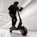 Person riding a black electric scooter with yellow accents in a modern indoor setting.